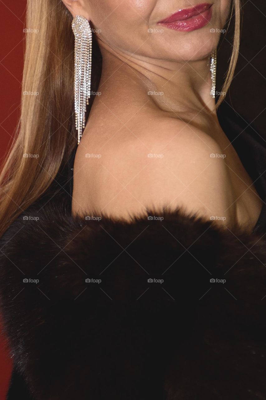Gorgeous woman in a fur coat and earrings with rhinestones.