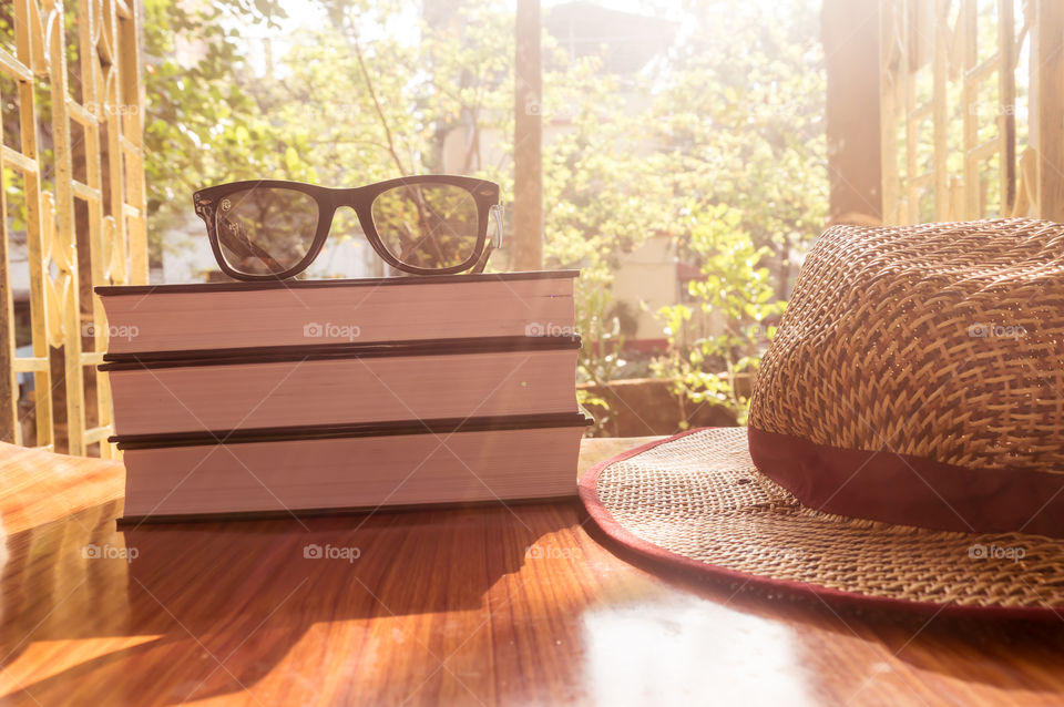 Front Side View Of Book and sunglasses with a straw hat. Summer holiday vacation background concept.