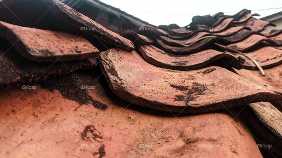 View of old school roof tiles made of clay on the roof of a house with a rickety bamboo frame, clay tiles that are generally installed on houses in Indonesia.