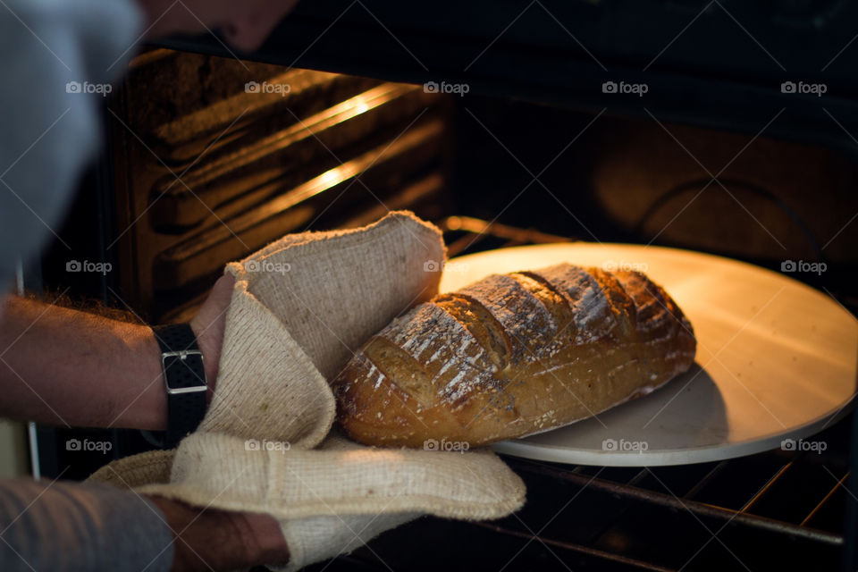 Homemade freshly baked sourdough bread - made at home and so delicious! Image of man taking sourdough bread out of the oven.