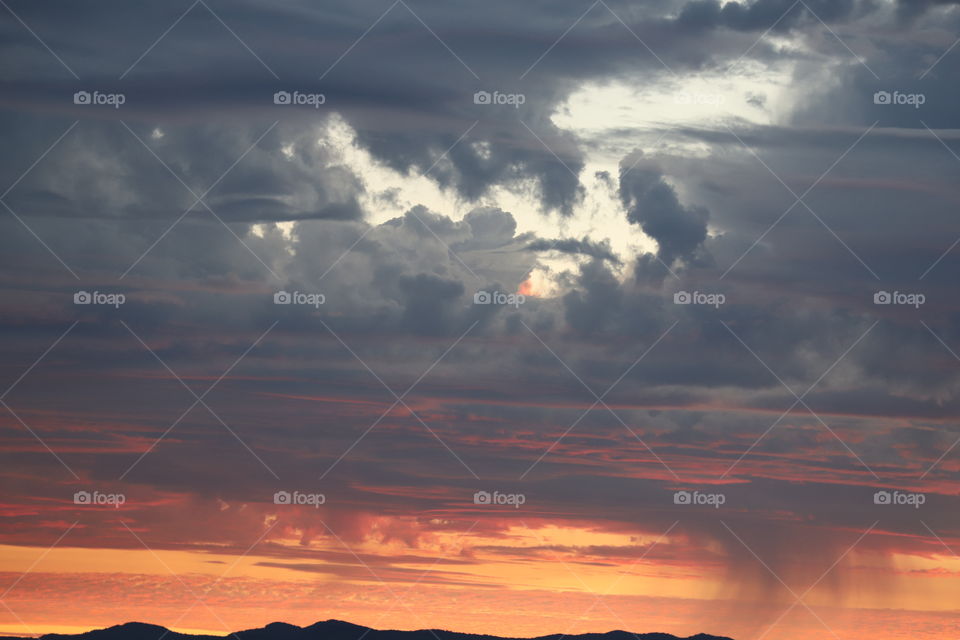 Dark clouds coming after perfect sunset pouring scattered showers over the mountains 