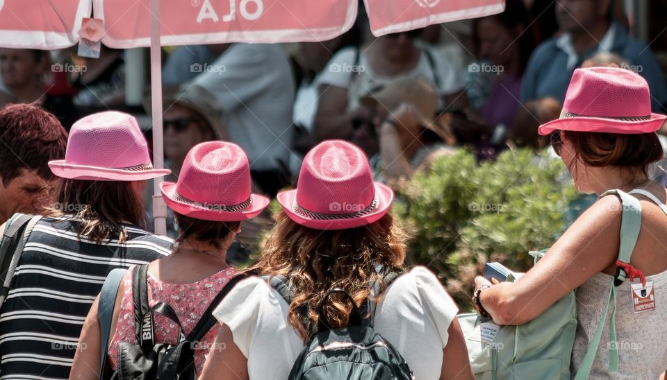 4 women in pink hats buying ice creams from a street vendor 