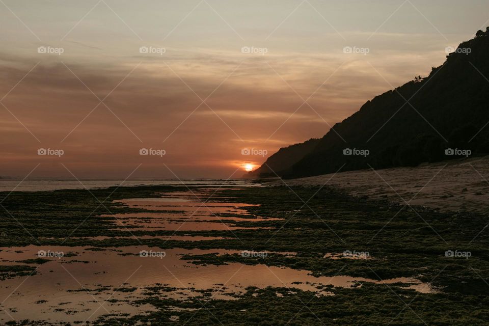 The sun is setting over the water at the beach