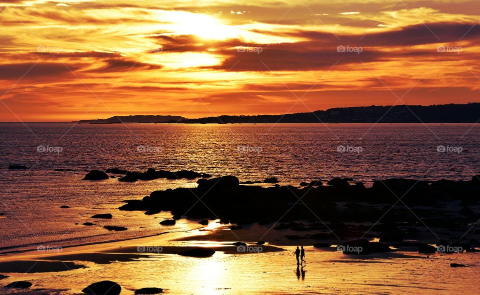 Silhouette of two people walking at beach