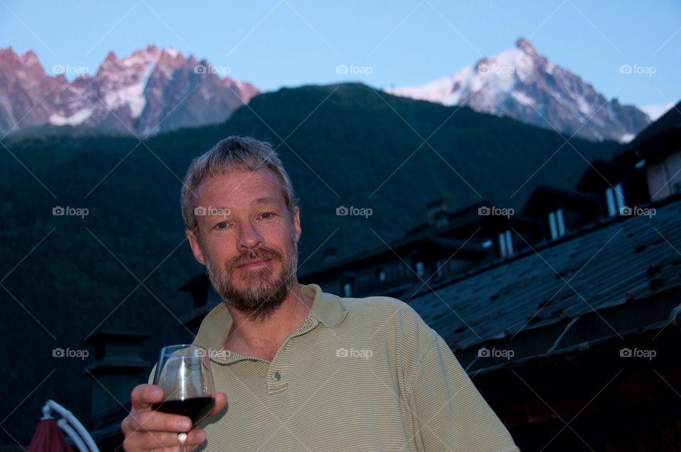 Man drinks a glass of wine in front of the snowcapped mountains