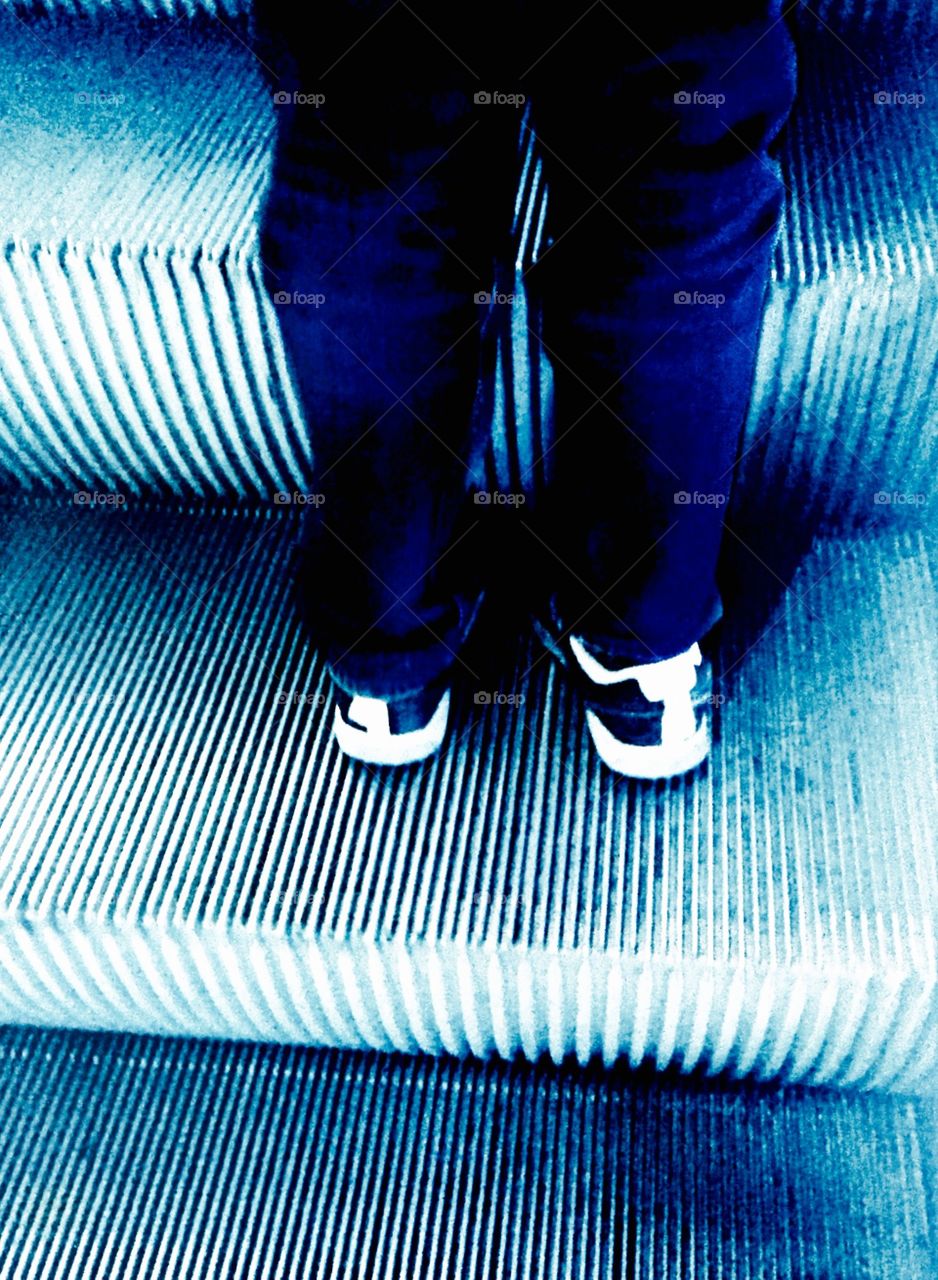Feet on escalator . Stood behind my son going some neon escalators.