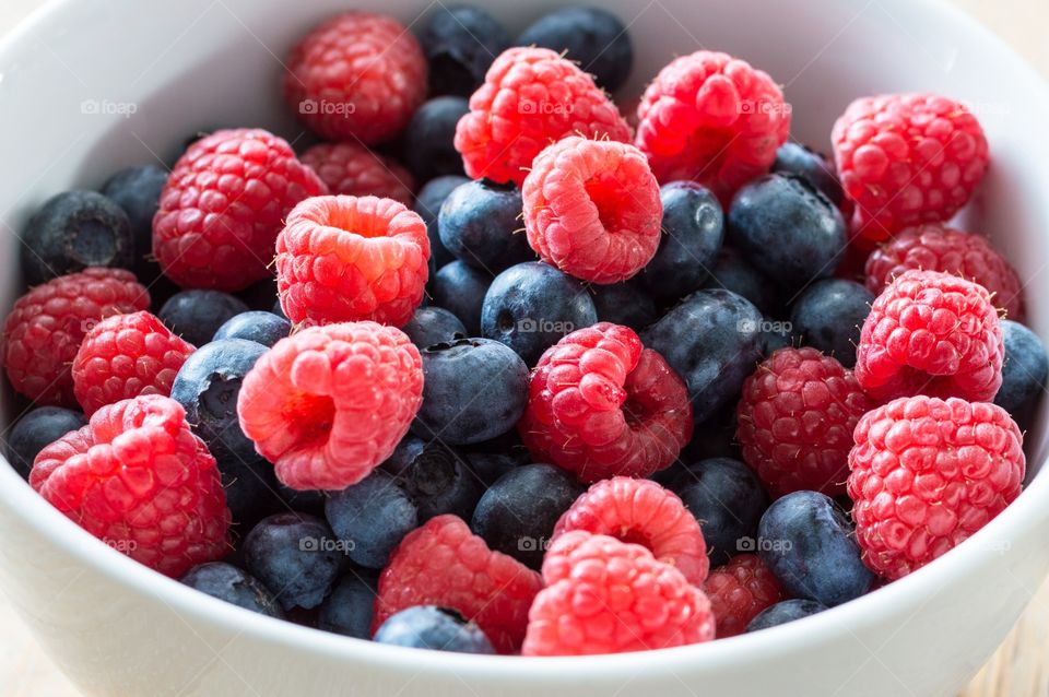 Close up of fresh blueberries and raspberries in a bowl.