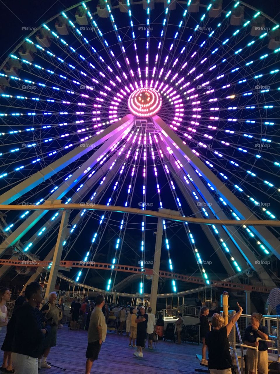 LED colorful Ferris wheel lit up in an array of colors as they people waited to go for a ride. 
