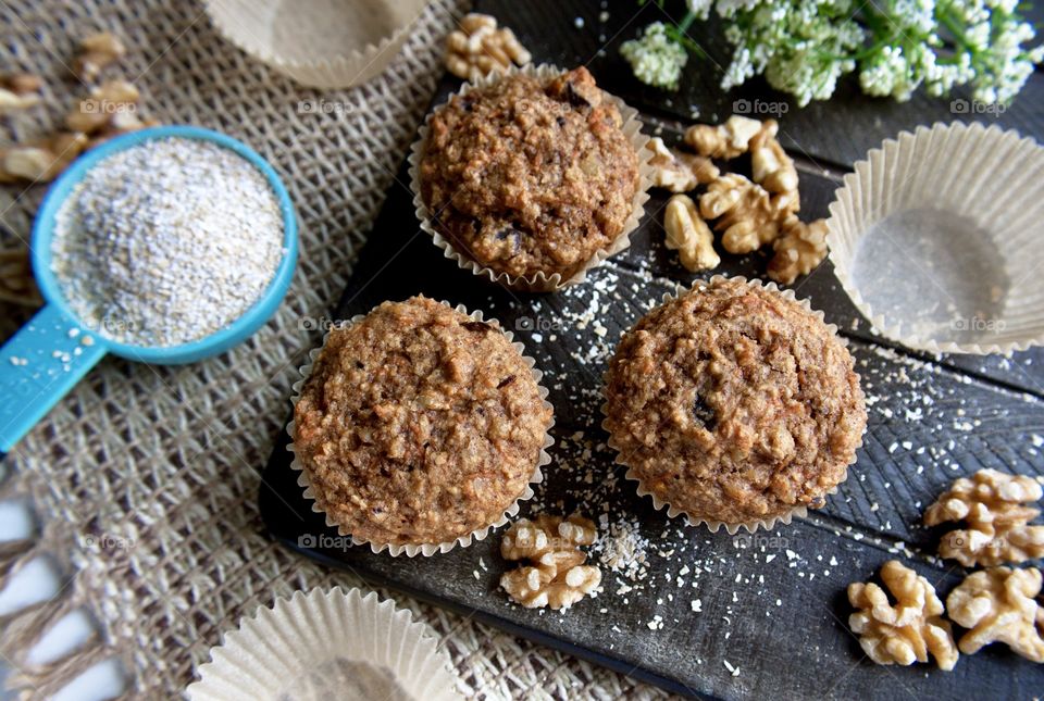 Tasty homemade oat bran muffins with walnuts on a wooden board.
