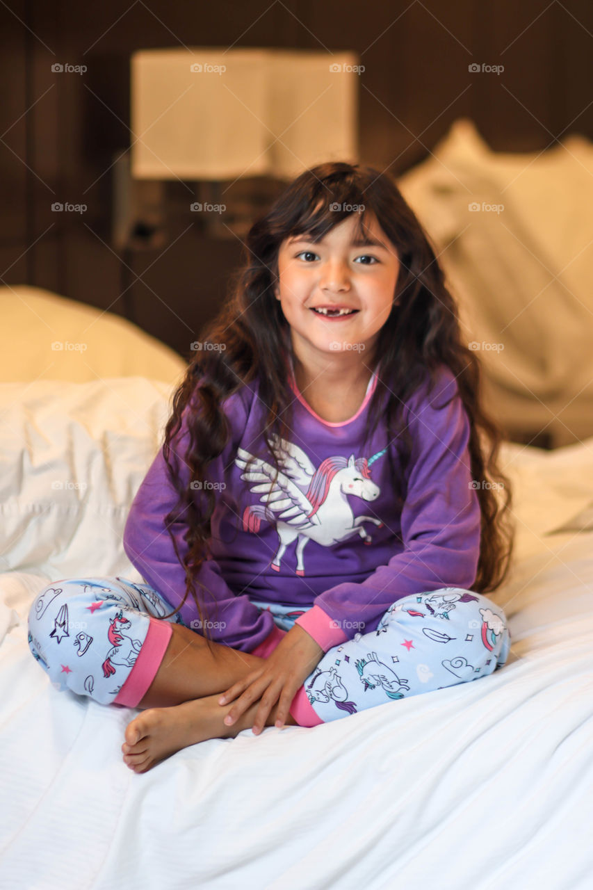 Cute little girl in pajamas with unicorns and rainbows