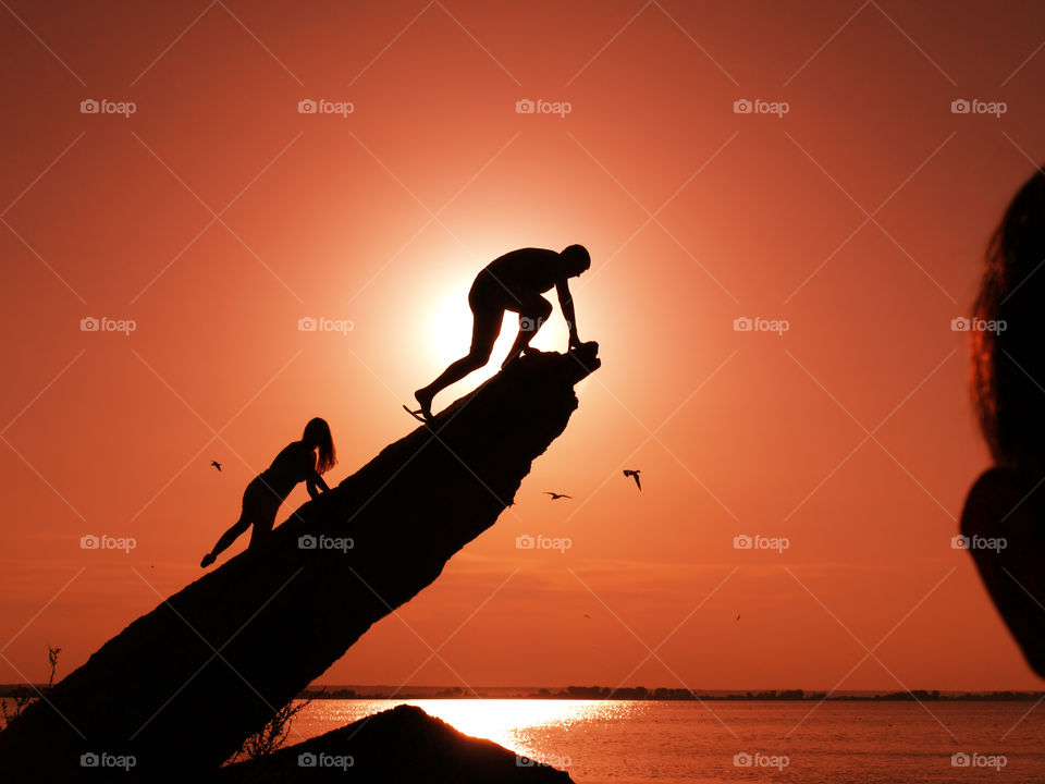 Two silhouettes on the rocks, sunset background