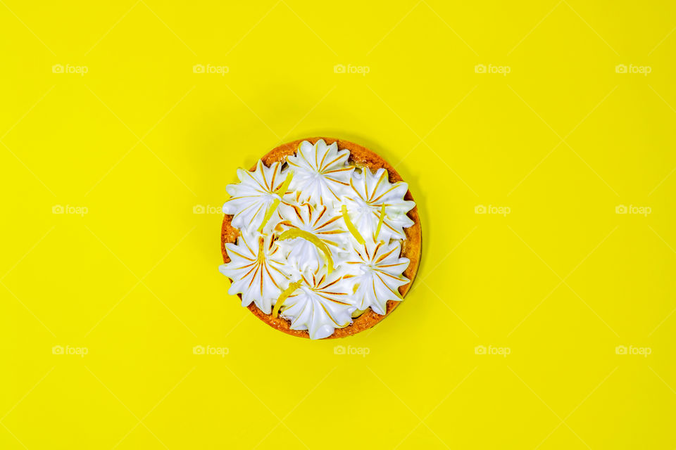 Top view to lemon tartlett with meringue on yellow background. Copy space.