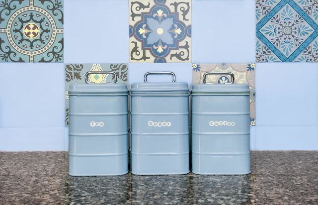Baby blue kitchen containers on a granite worktop in front of pastel shade tiles