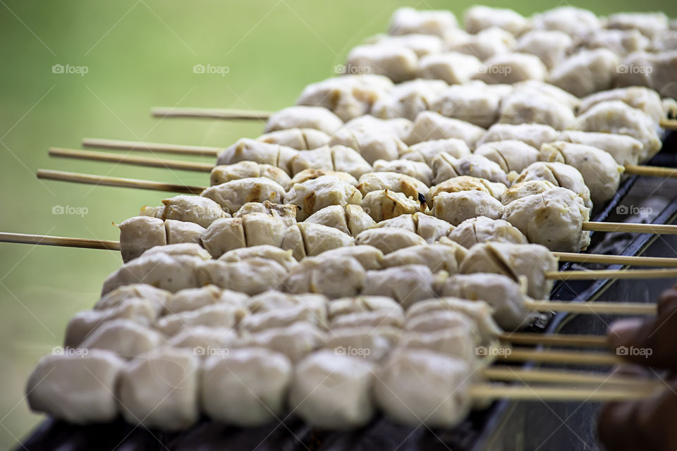 Grilled pork meatballs on the grill , charcoal is on fire.