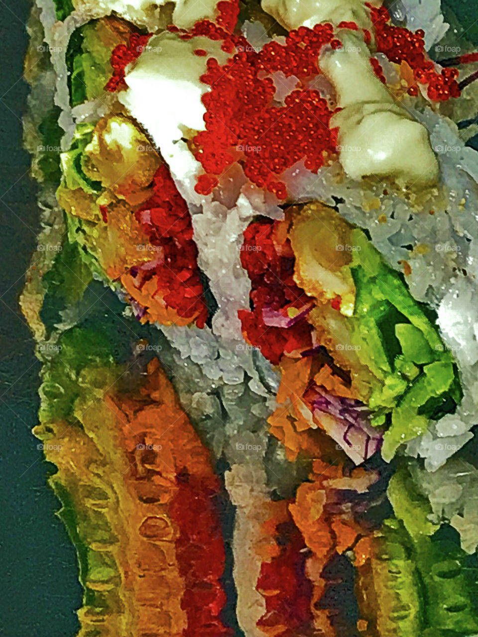 Closeup of colourful red, green, orange, yellow, white & black Calamari sushi on a reflective silver plate under a restaurant table spotlight. The bright colours and textures are only slightly blurred in the reflection producing an abstract effect. 🥢