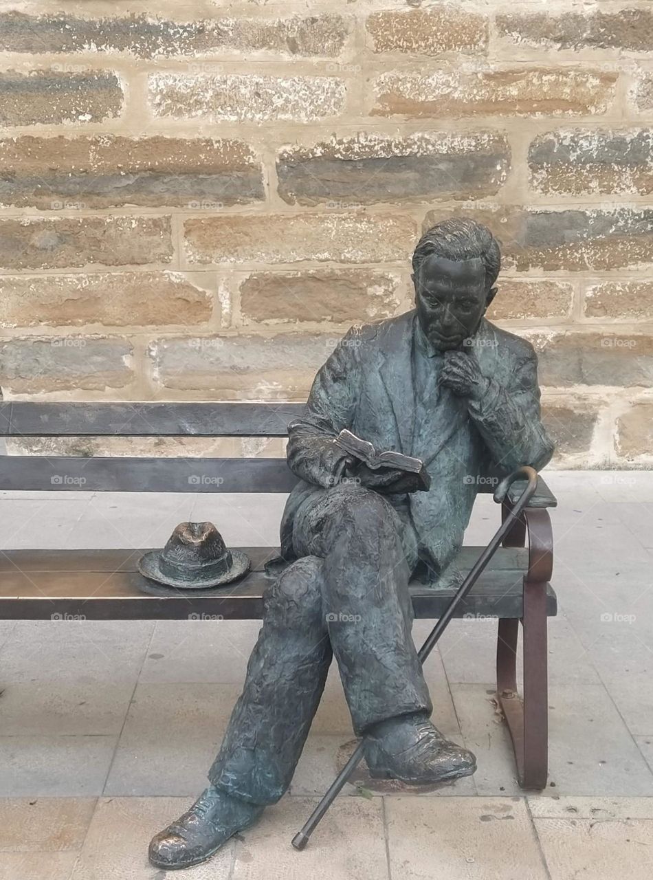 Escultura de hombre lleendo un libro