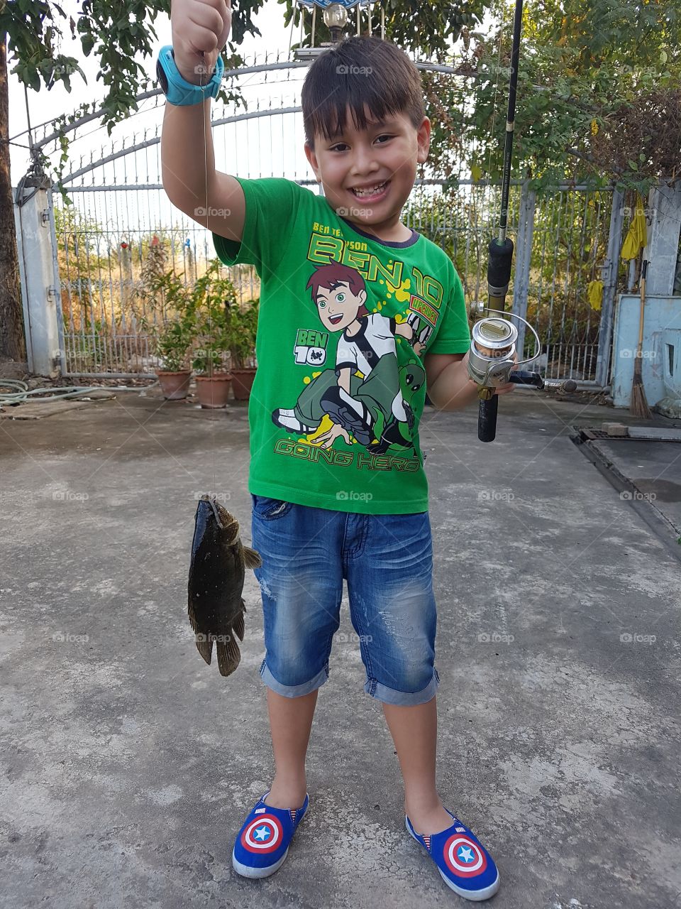 young boy proudly showing off his catch, a fresh river fish