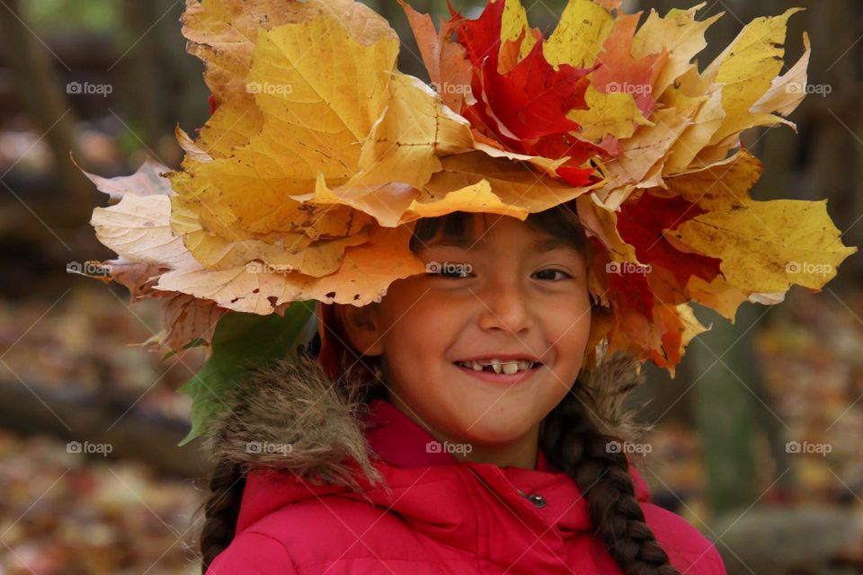 Cute girl in a crown of autumn leaves