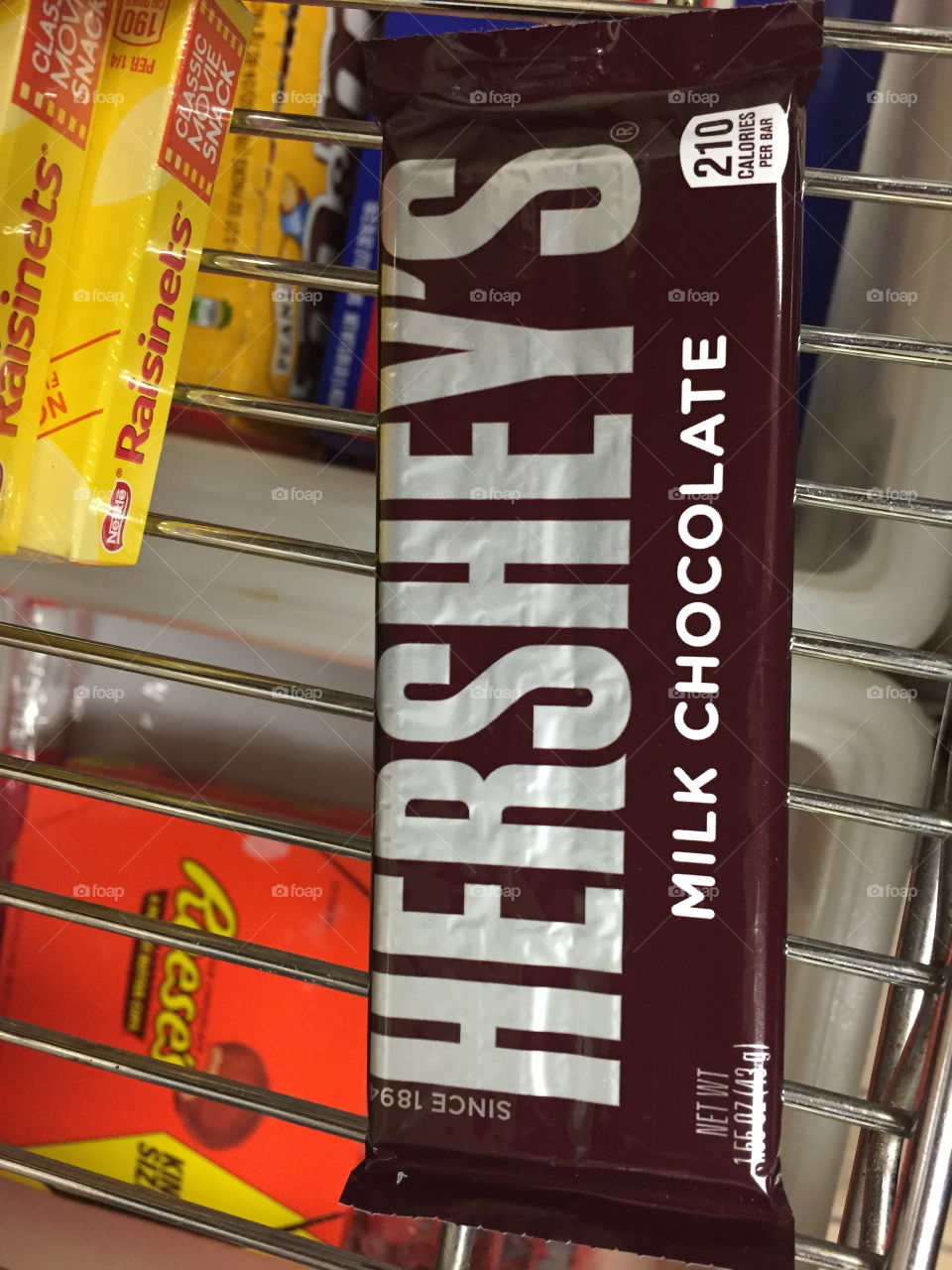 Close up of a Hershey chocolate bar with other candy on a silver rack. 