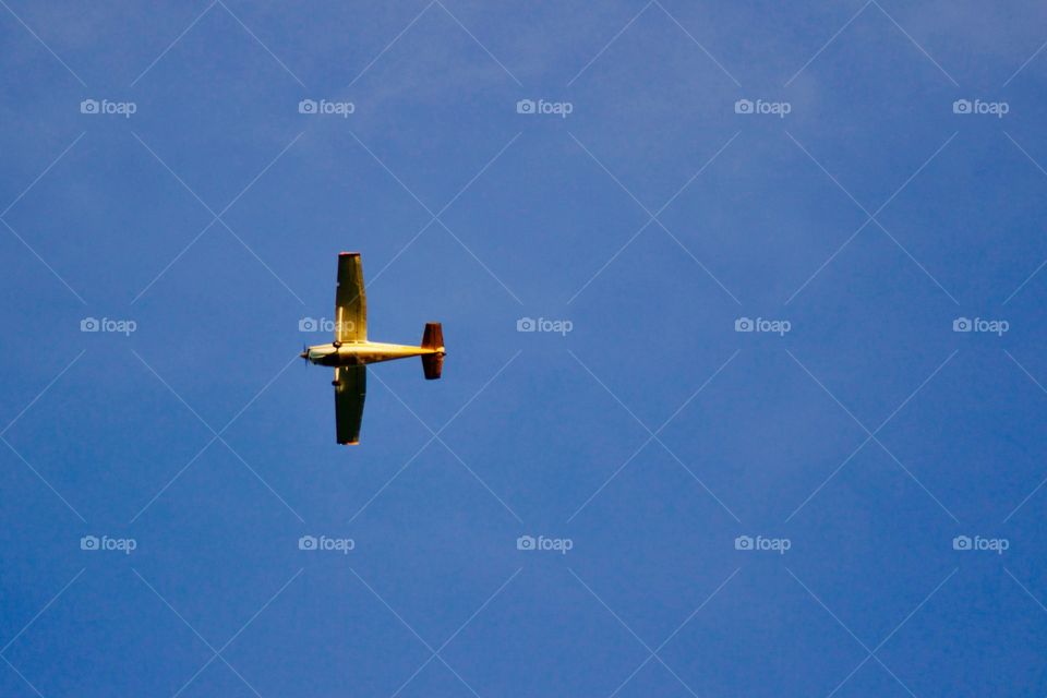 A single-engine plane passes by overhead against a deep blue sky 