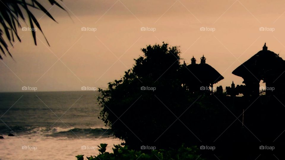 Pura Tanah Lot, a popular tourist destination and favorite cultural icon for photography, sits on a large offshore rock which has been shaped continuously over the years by the ocean tide.