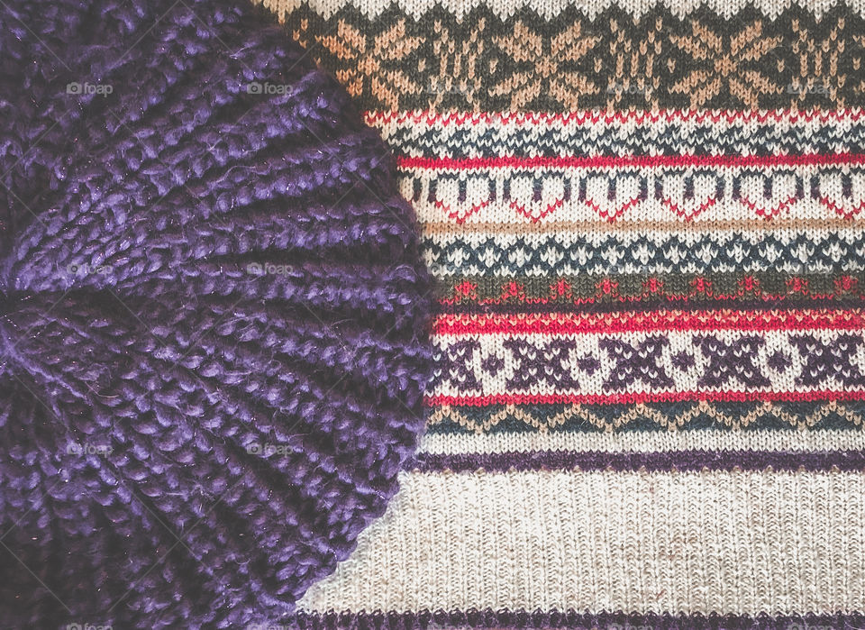 A purple knitted beret on top of a colourful, patterned knitted jumper