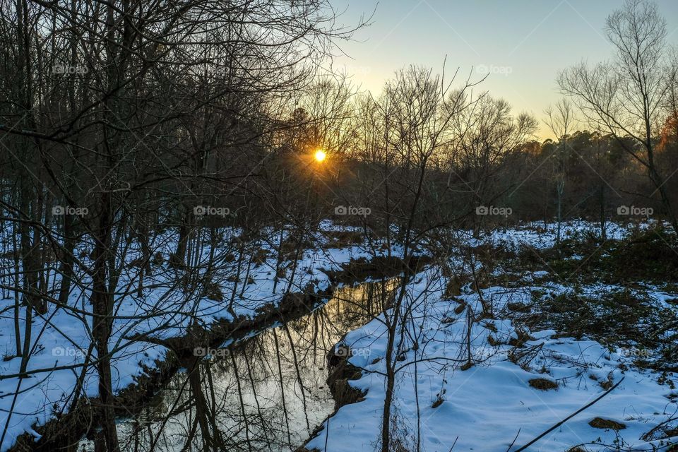 Sunset over a snowy creek at Yates Mill County Park, Raleigh, North Carolina. 