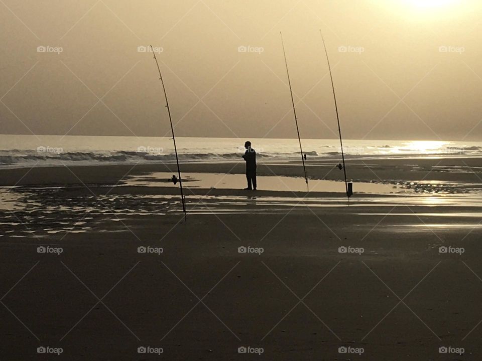 A fisherman at low tide in evening light 