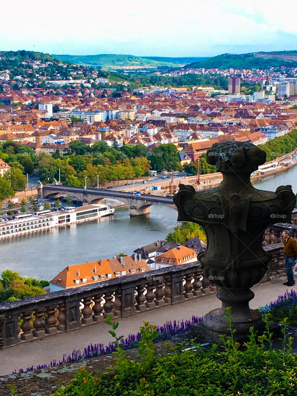Overlooking a beautiful, colorful city in the middle of Germany in late summer. A bridge off in the distance spans a river next to a colorful city.