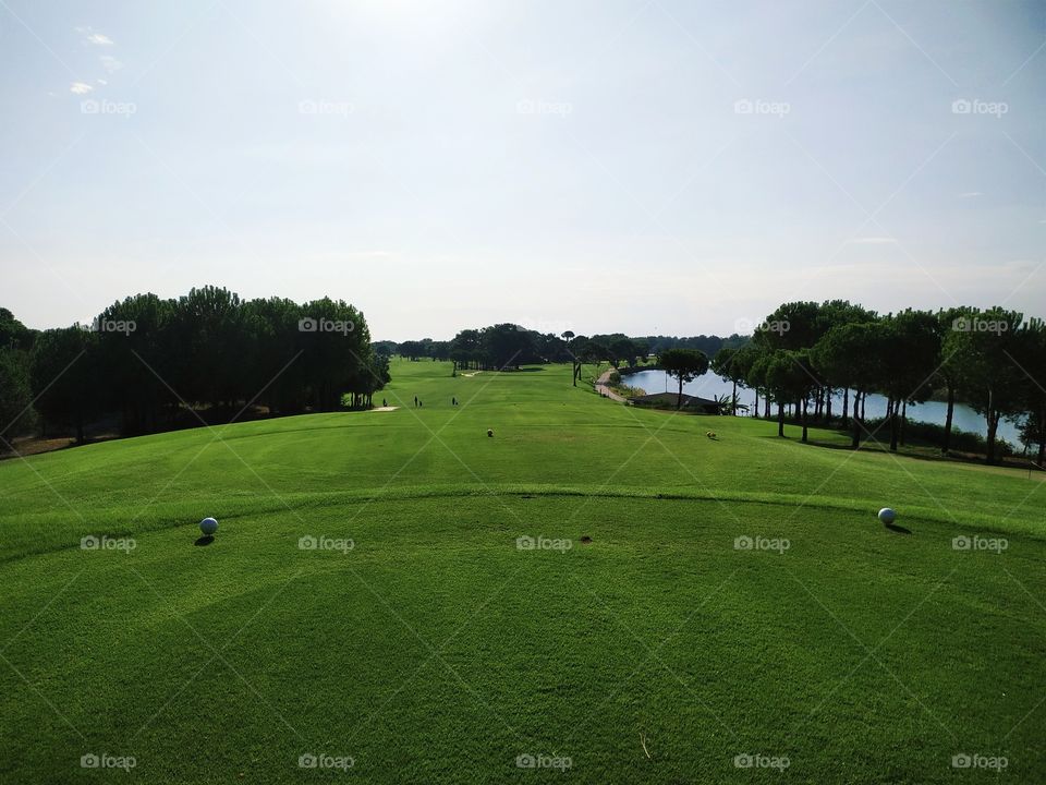 A beautiful view from the tee box to the downhill elevated golf hole with trees and river.