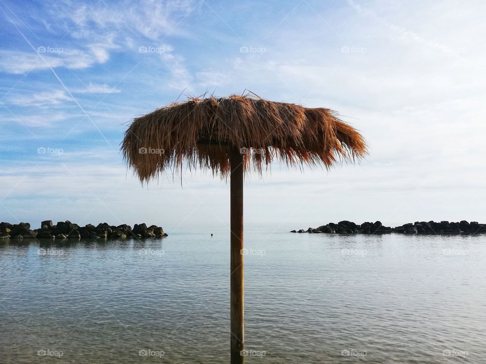 Straw beach umbrella in the middle of the sea