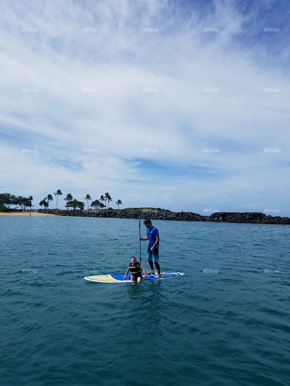 Boy gets a lesson on paddle boarding at Pokai Bay