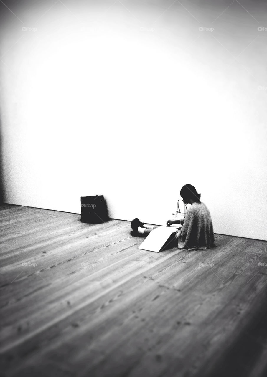A girl sitting in a gallery drawing.