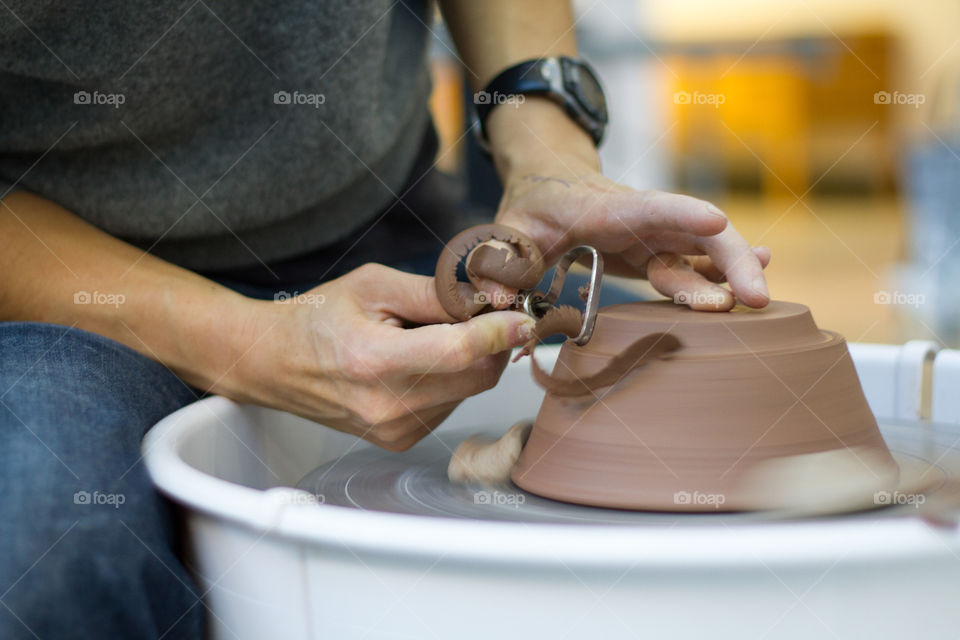 An artist works on a piece of pottery