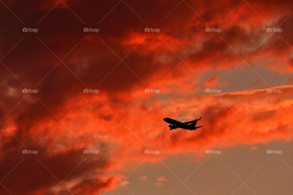 Silhouette of airplane flying in dramatic sky