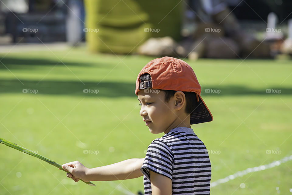 Portrait Asian boy holding grass and smiled happily on the lawn.