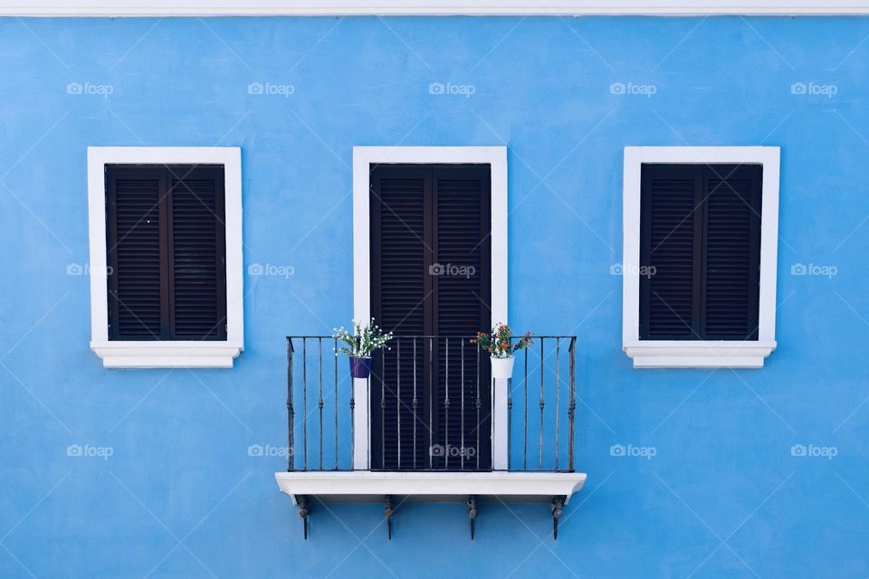 A balcony and two windows on a baby blue color wall