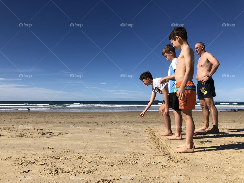 Family playing a game at the beach throwing stones in a competition on a sunny day 