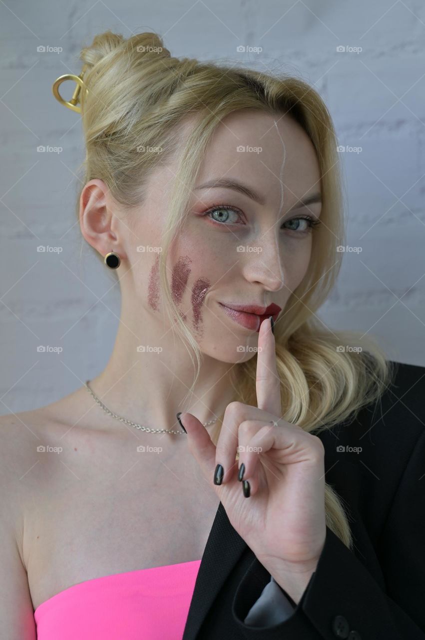 Close-up portrait of a blonde smiling girl with different make-up on half of her face which points to silence on white background