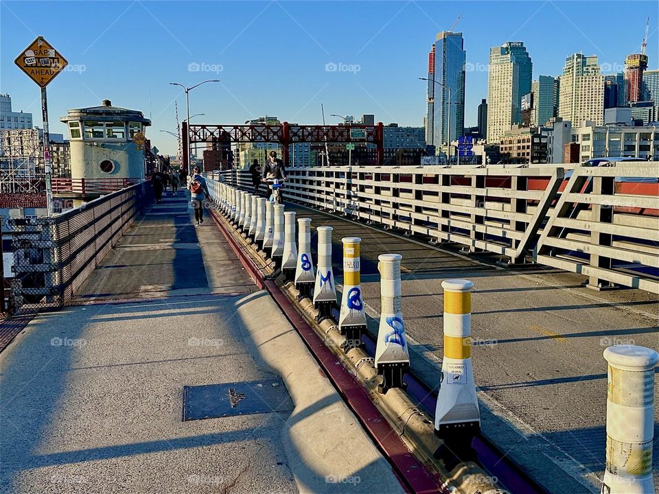 This is the pedestrian and the bicycle lane of the “Pulaski Bridge” at “Newtown Creek” that connects “Greenpoint”, Bklyn to LIC in the direction we are now headed. The setting sun accentuates the geometry of the bridge. 2024. Hypnotic Productions