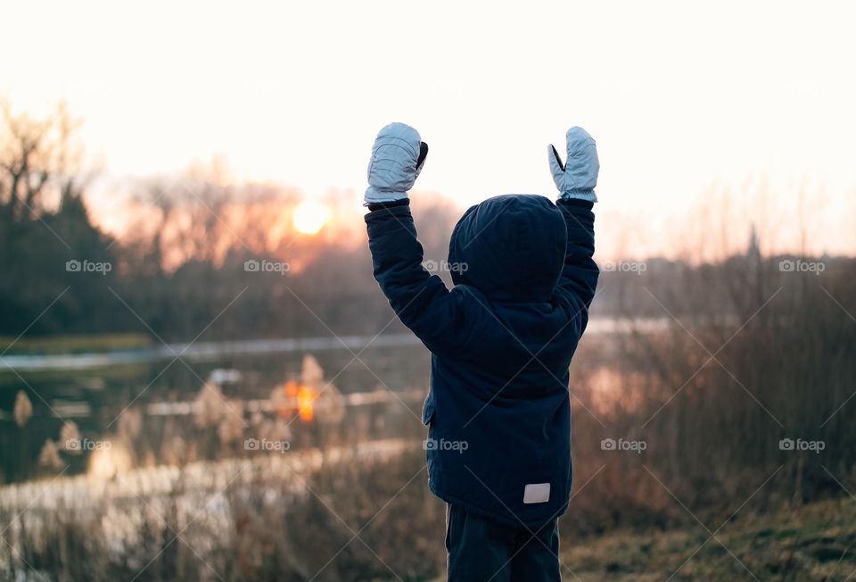 Rear view of a boy standing with armsraised