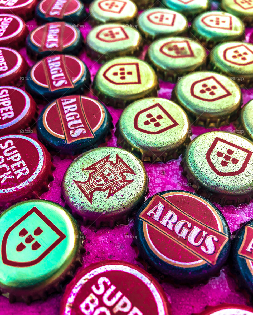 Metal beer bottle tops, stuck to a table, close up