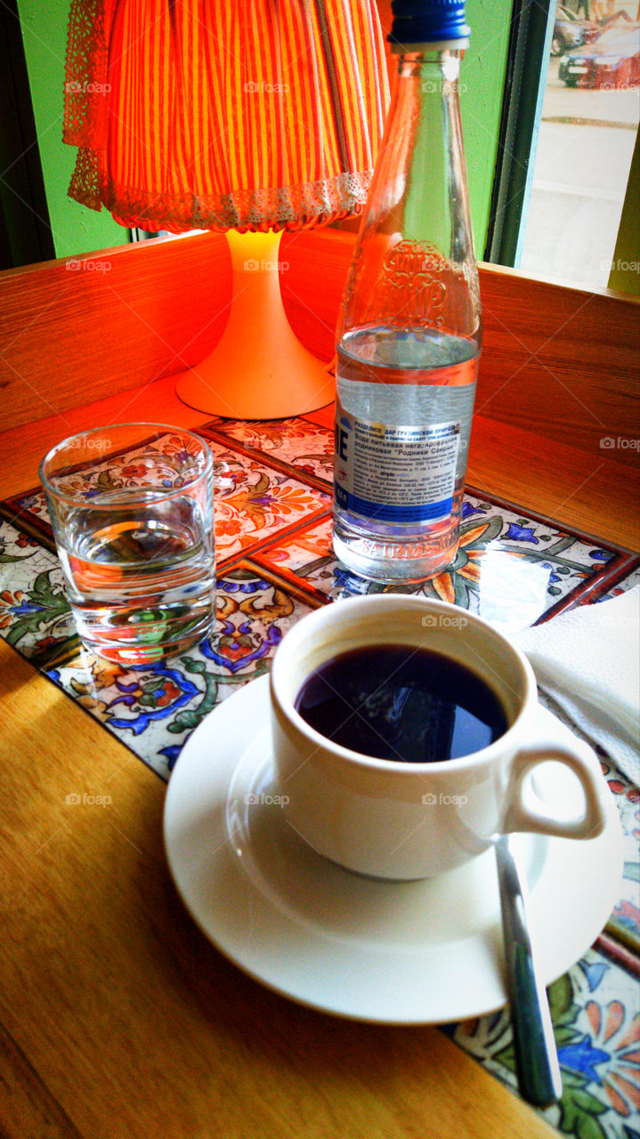 Cup of coffee, bottle of water and lamp