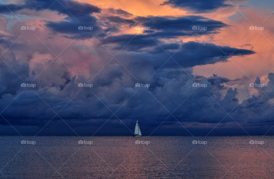 white sailboat on the dramatic cloudy sky background during sunset over the baltic sea in poland