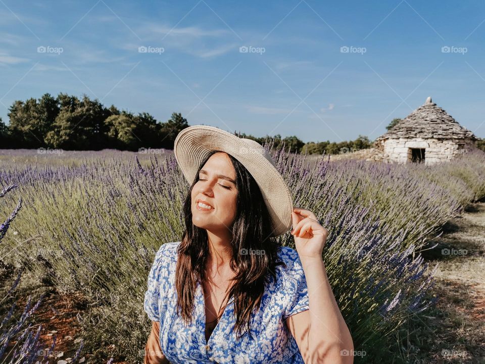 Portrait of a young woman wearing sun hat and dress, relaxing outdoor in a lavender field