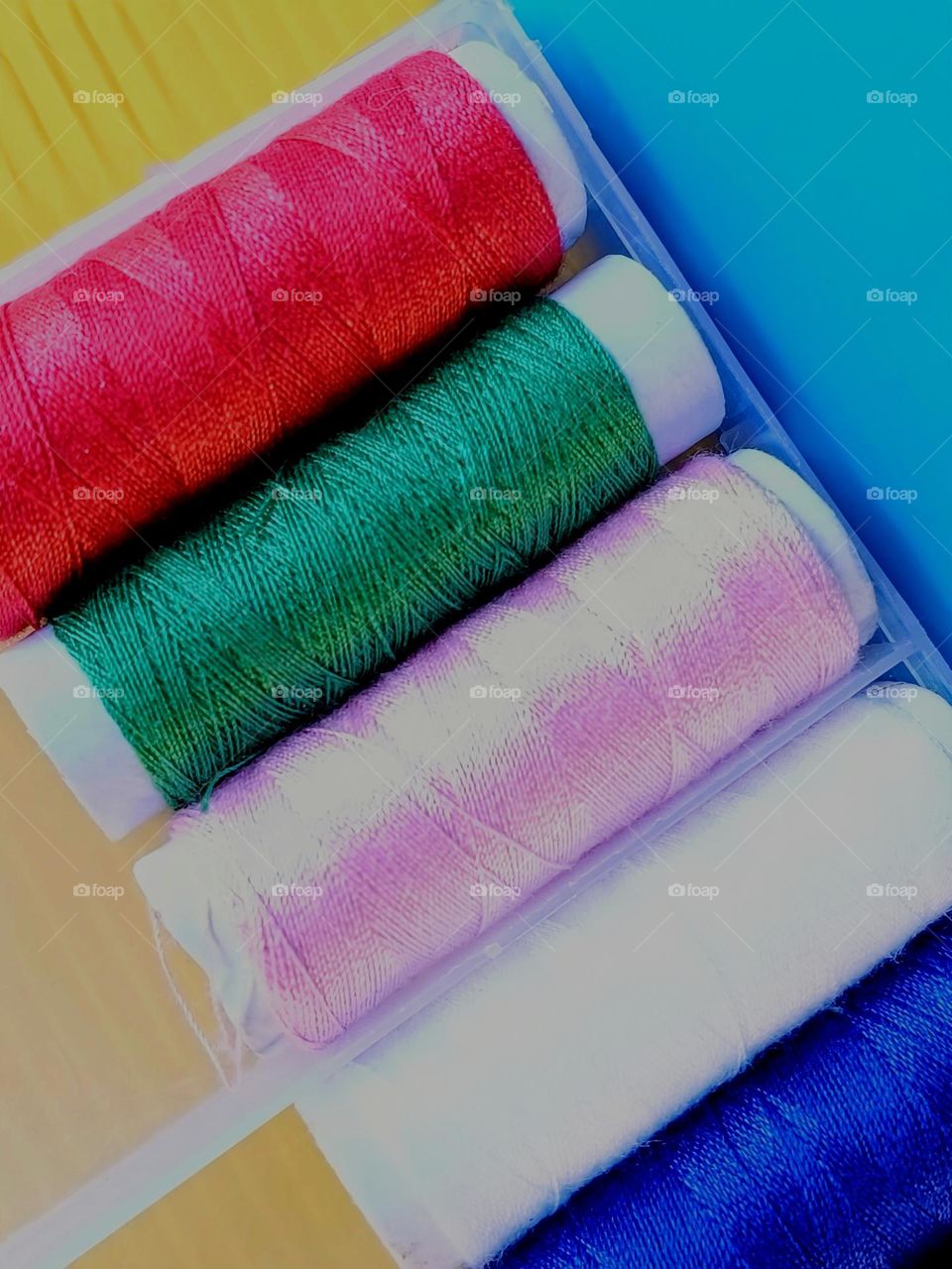 Close up of colorful threads on blue and yellow background.