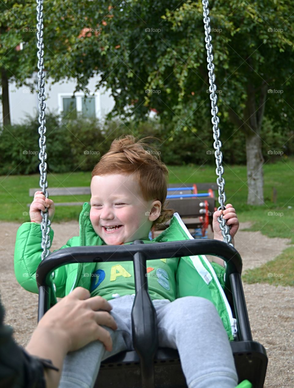 Mother pushing son on swing