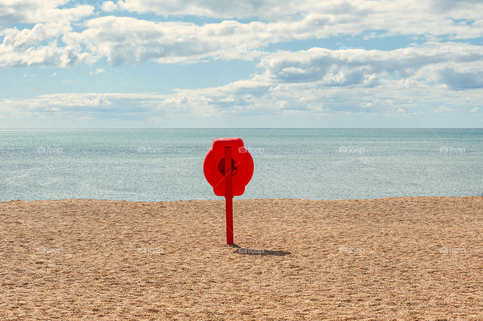 Sea life safely equipment, red lifebuoy on beach.