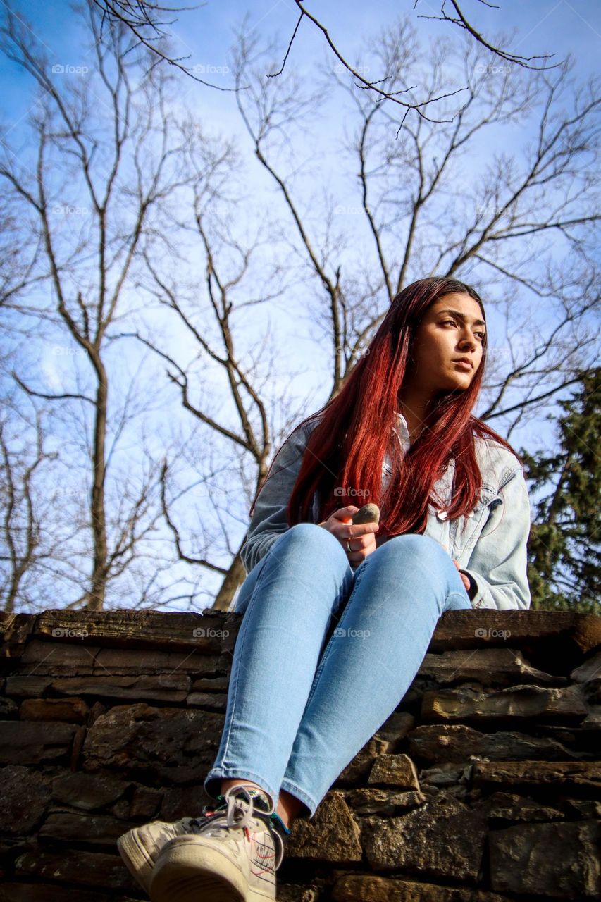 Young redhead woman is sitting outside