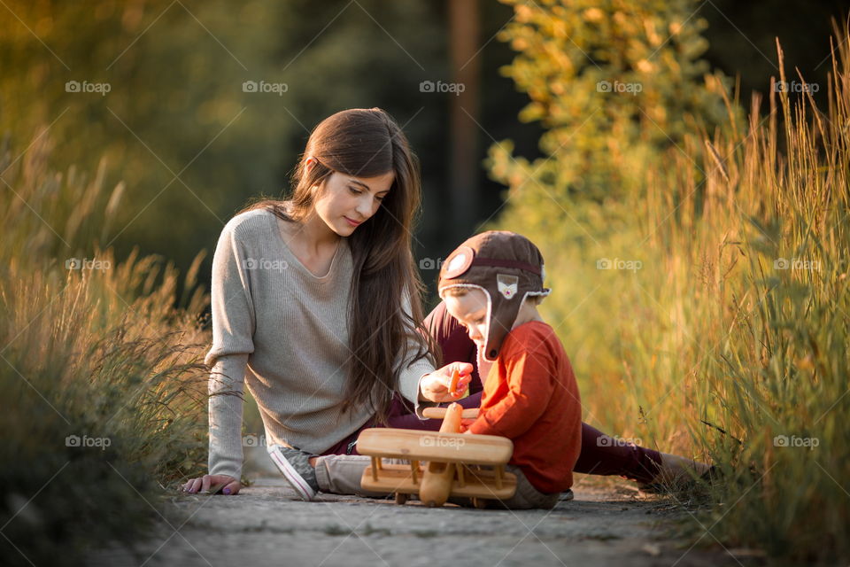 Mother and son with wooden plane at sunset